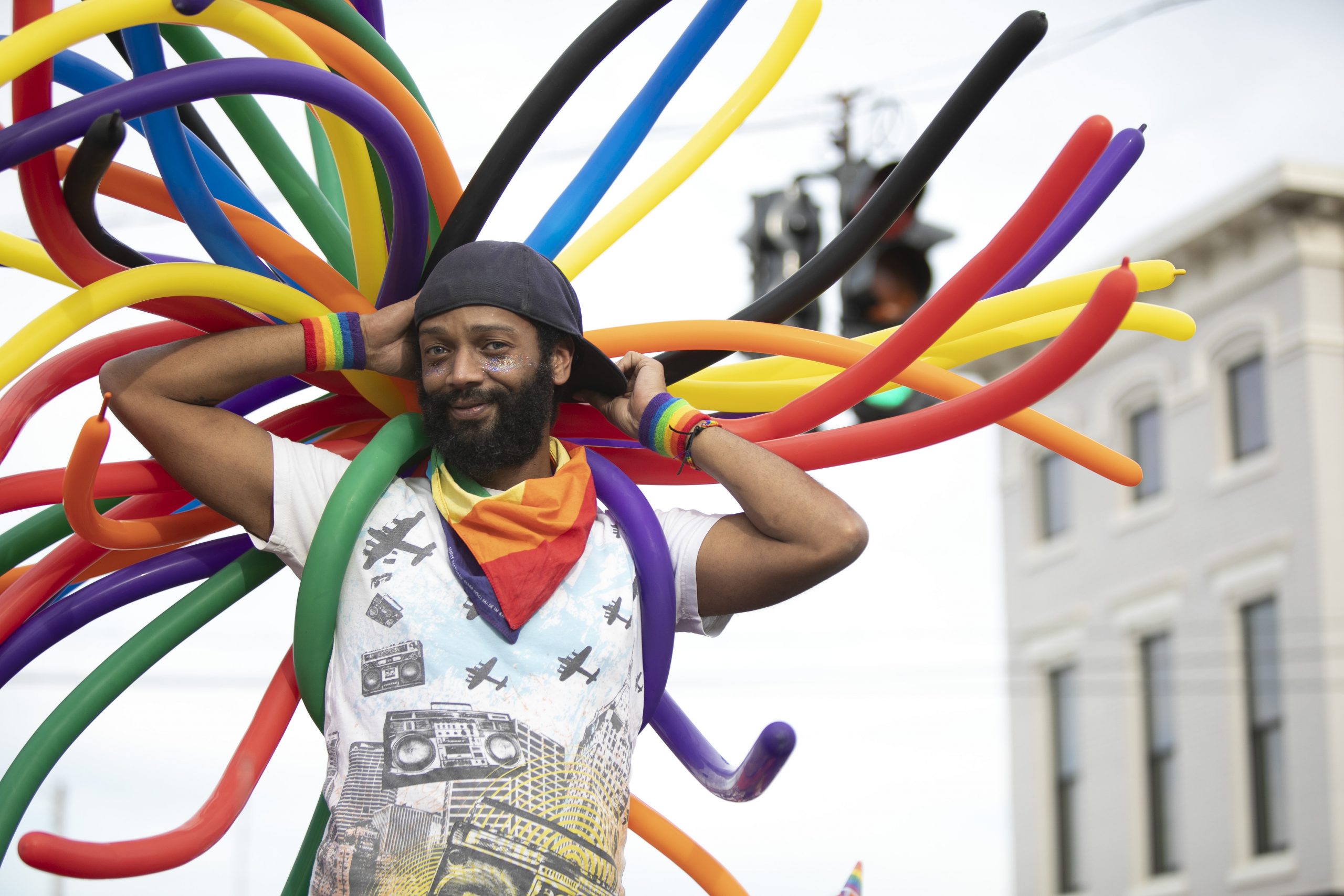 Smiling man holding multi-colored balloons.