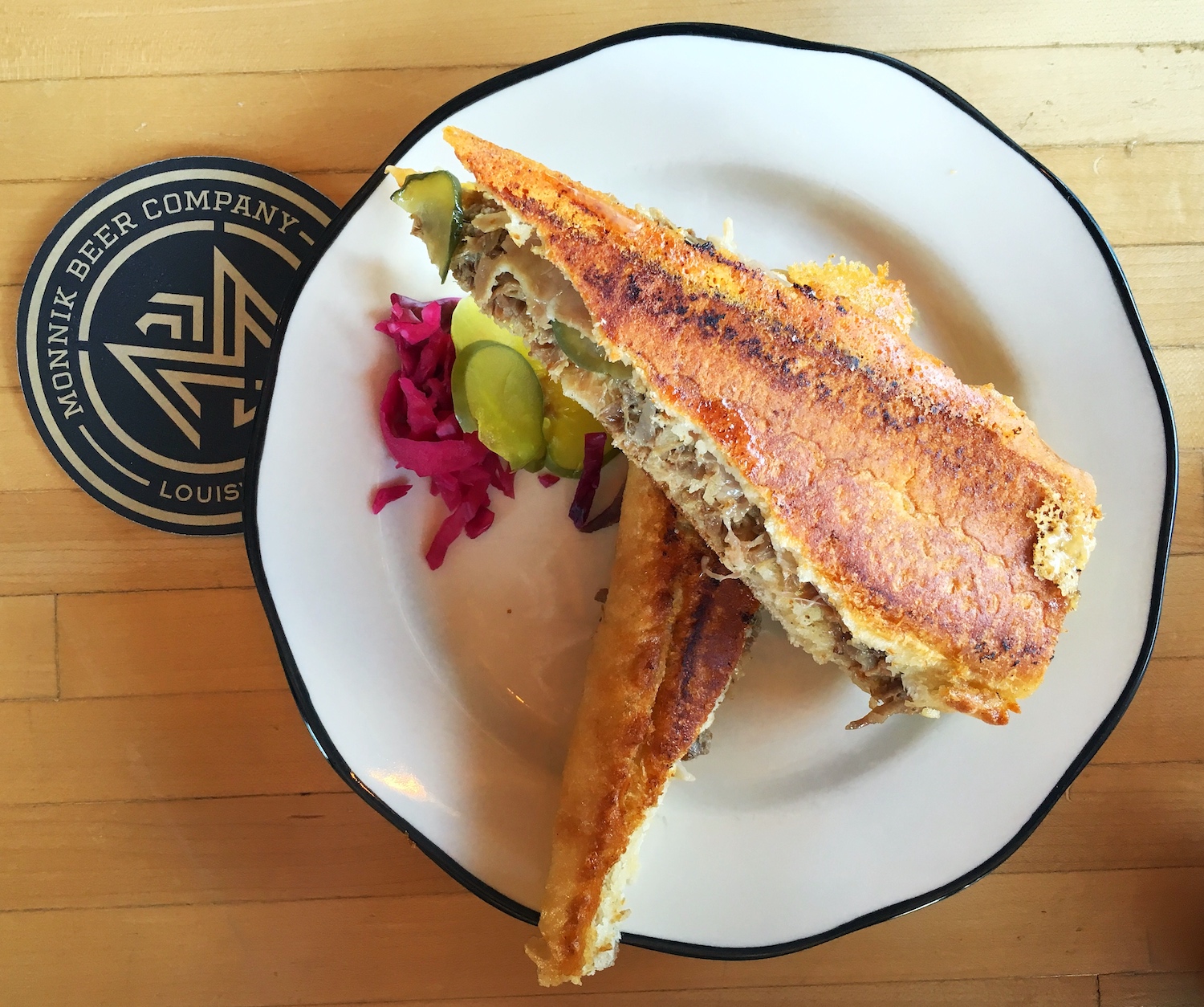 cuban sandwich with a coaster next to it reading "Monnik Beer Company"