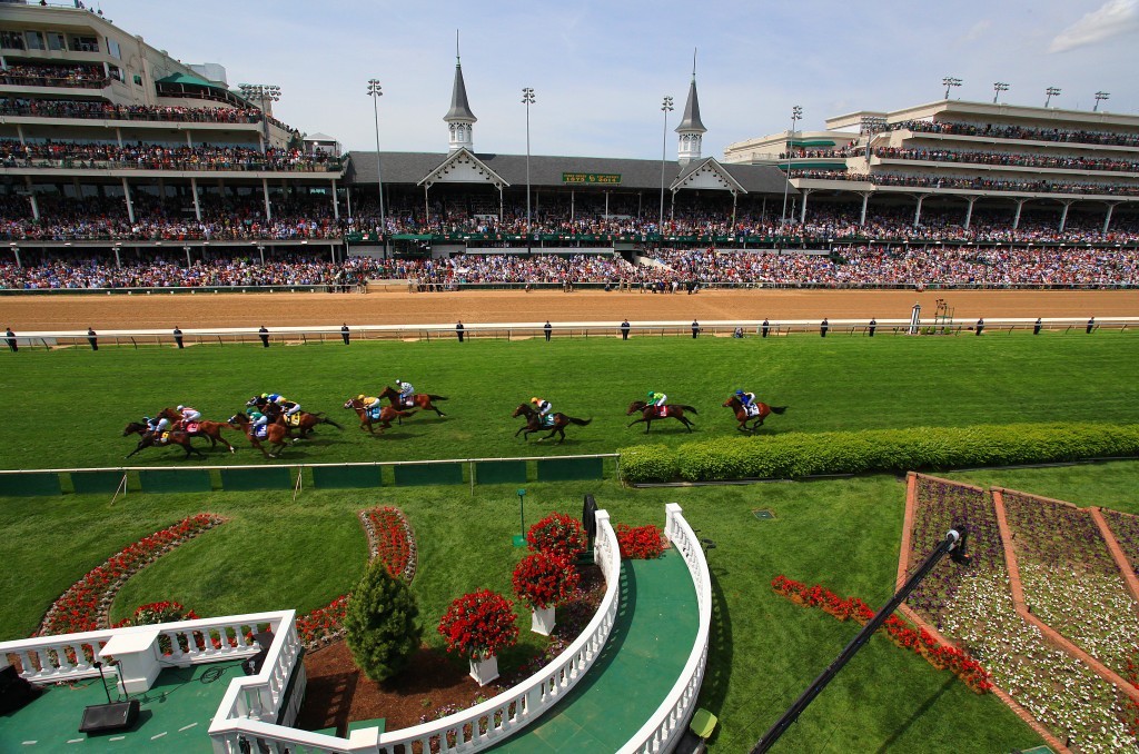 horses racing at the kentucky derby with the spires of Churchill Downs in the background