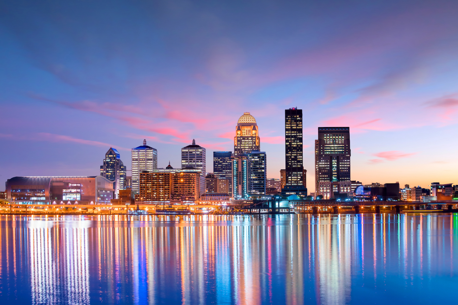 The Louisville skyline lit against a pastel dawn on the river.