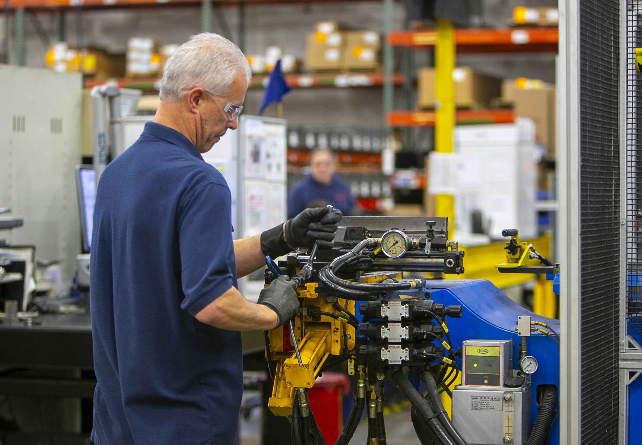 silver-haired gentleman adjusting a piece of machinery